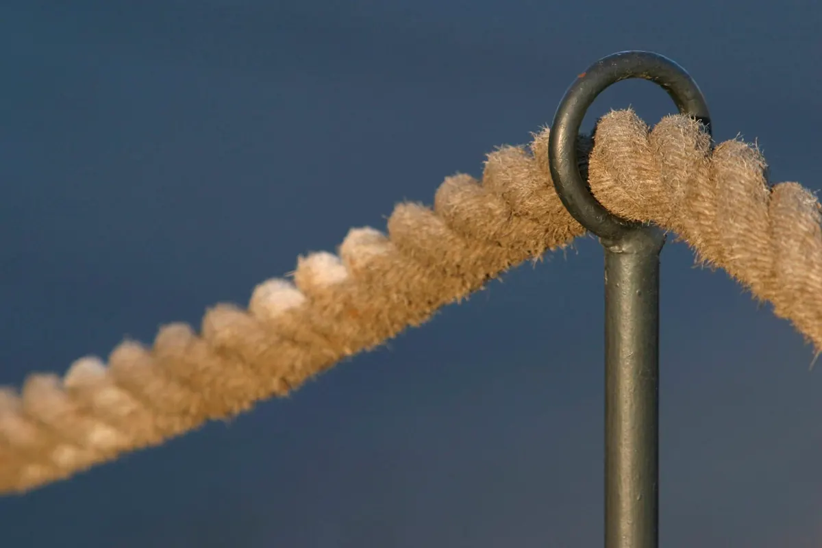 Une corde tendue passant dans un anneau métallique, symbole d'un cadre solide